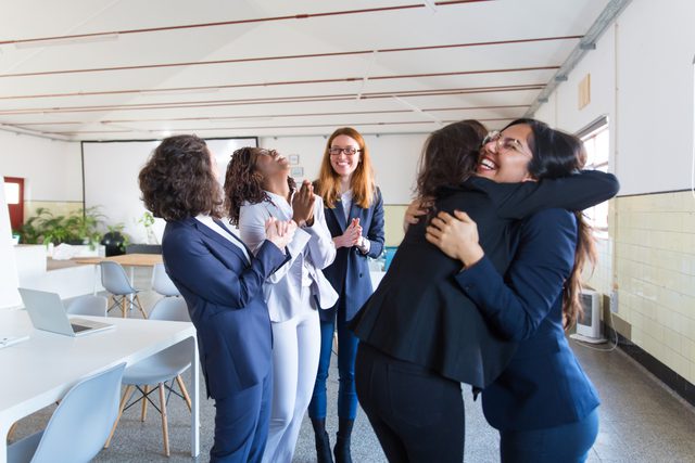 Mujeres ejecutivas compartiendo con alegría